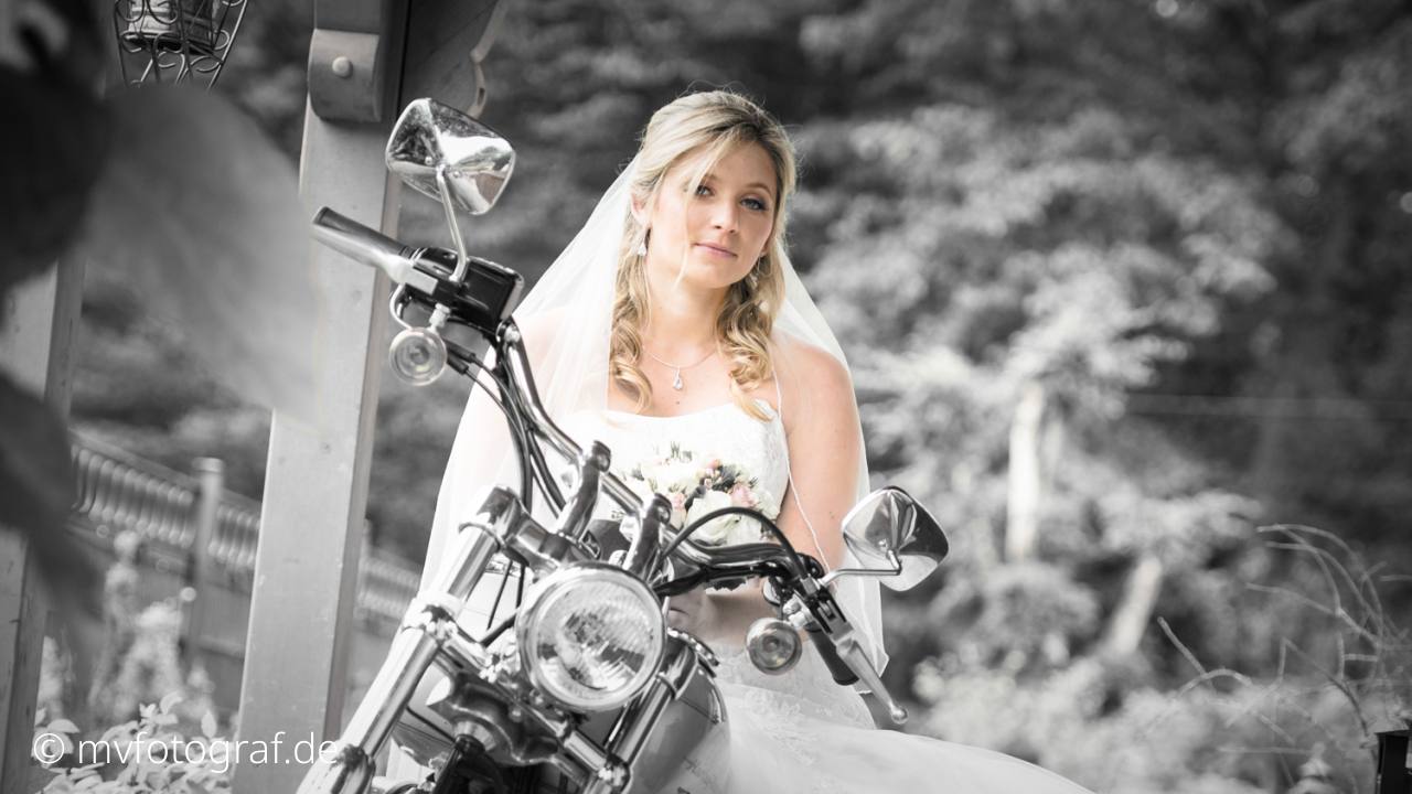Eine Frau mit Brautschleier sitzt auf einem Motorrad