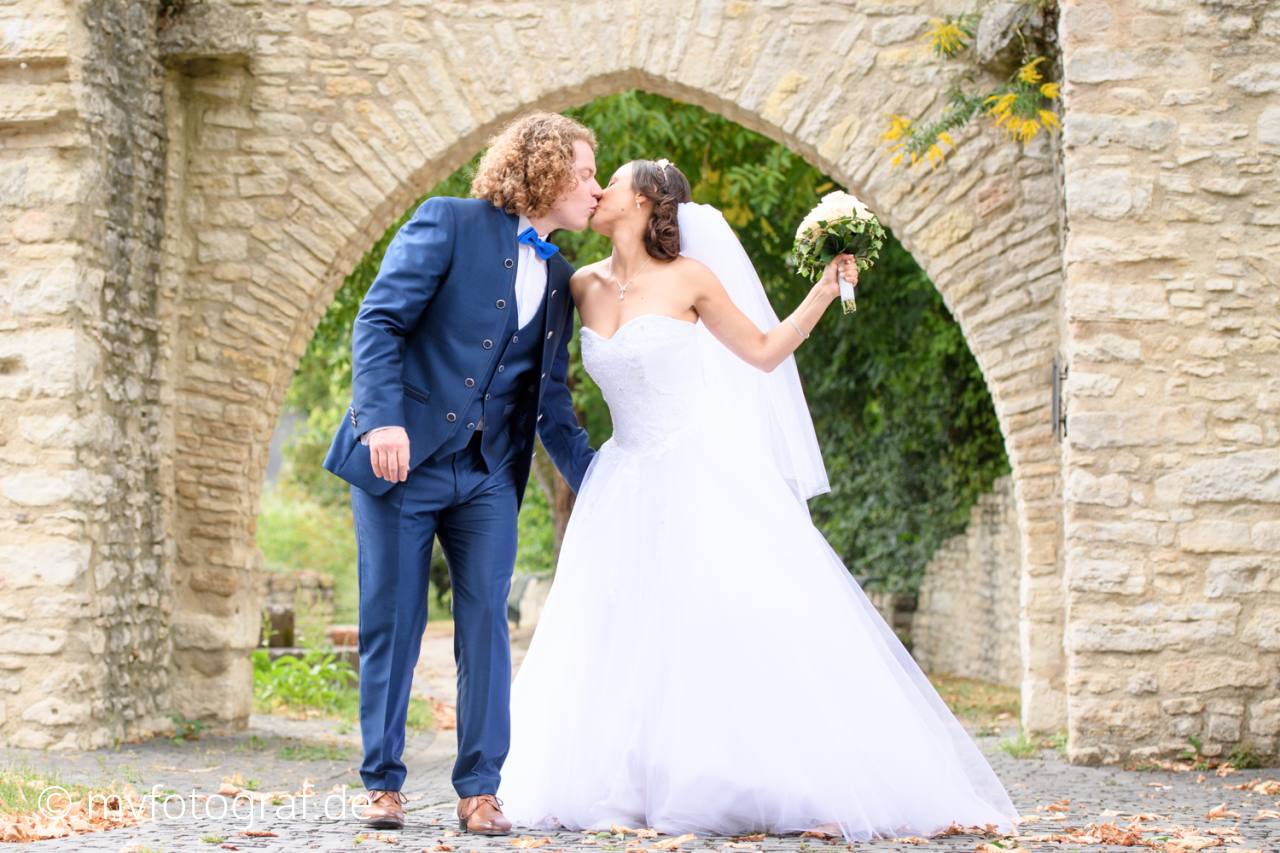 Ein Brautpaar gibt sich beim spazieren einen Kuss