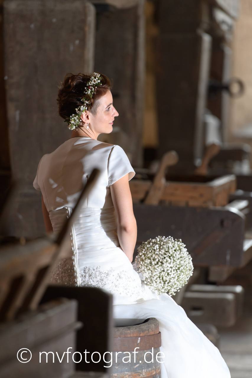 Braut an Presse Eine Frau im weißen Hochzeitskleid sitzt auf einem Weinfass