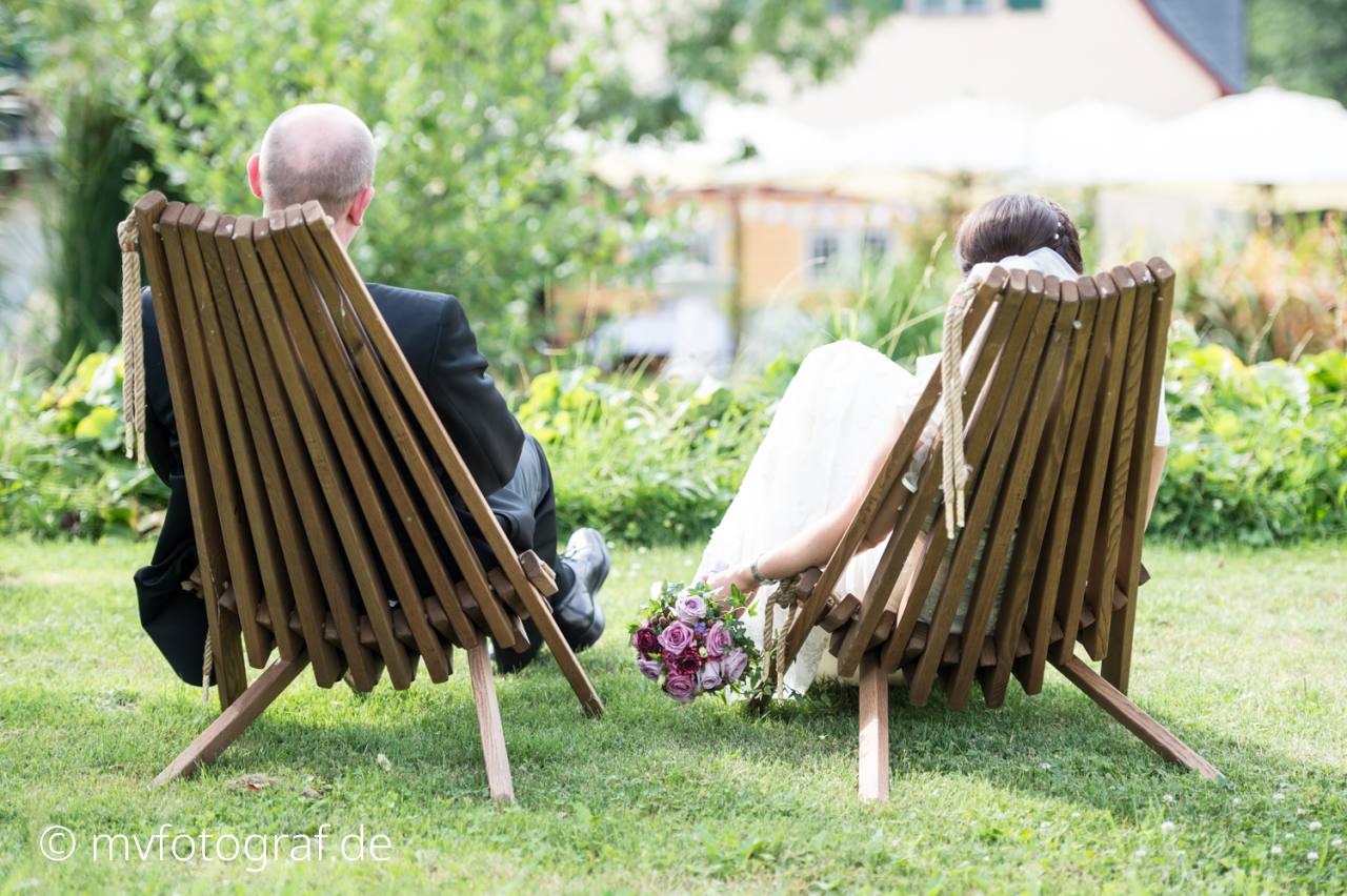 Brautpaar sitzt Ein Brautpaar sitzt auf einer Wiese im Gartenstühlen